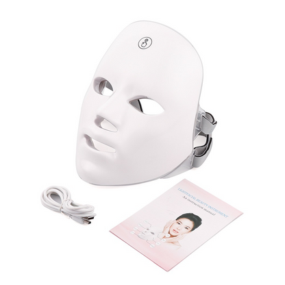 White facial beauty device with eye and mouth openings, USB charging cable, and user manual laid out flat.