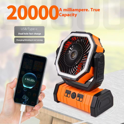 Orange and black outdoor household power bank fan with a front fan grill, LED light, and dual charging ports; being used to charge a smartphone.